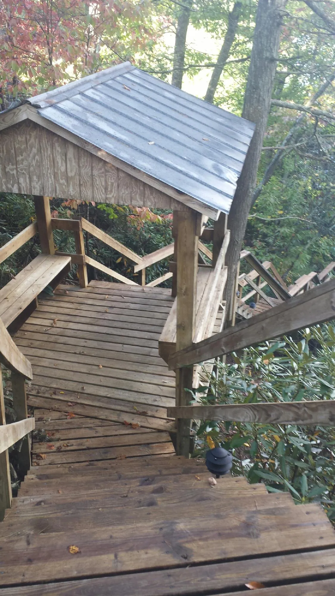Metal roofed shelter over wooden steps on a wooded walkway — Skylight Repair & Installation work by our crew in Claysville