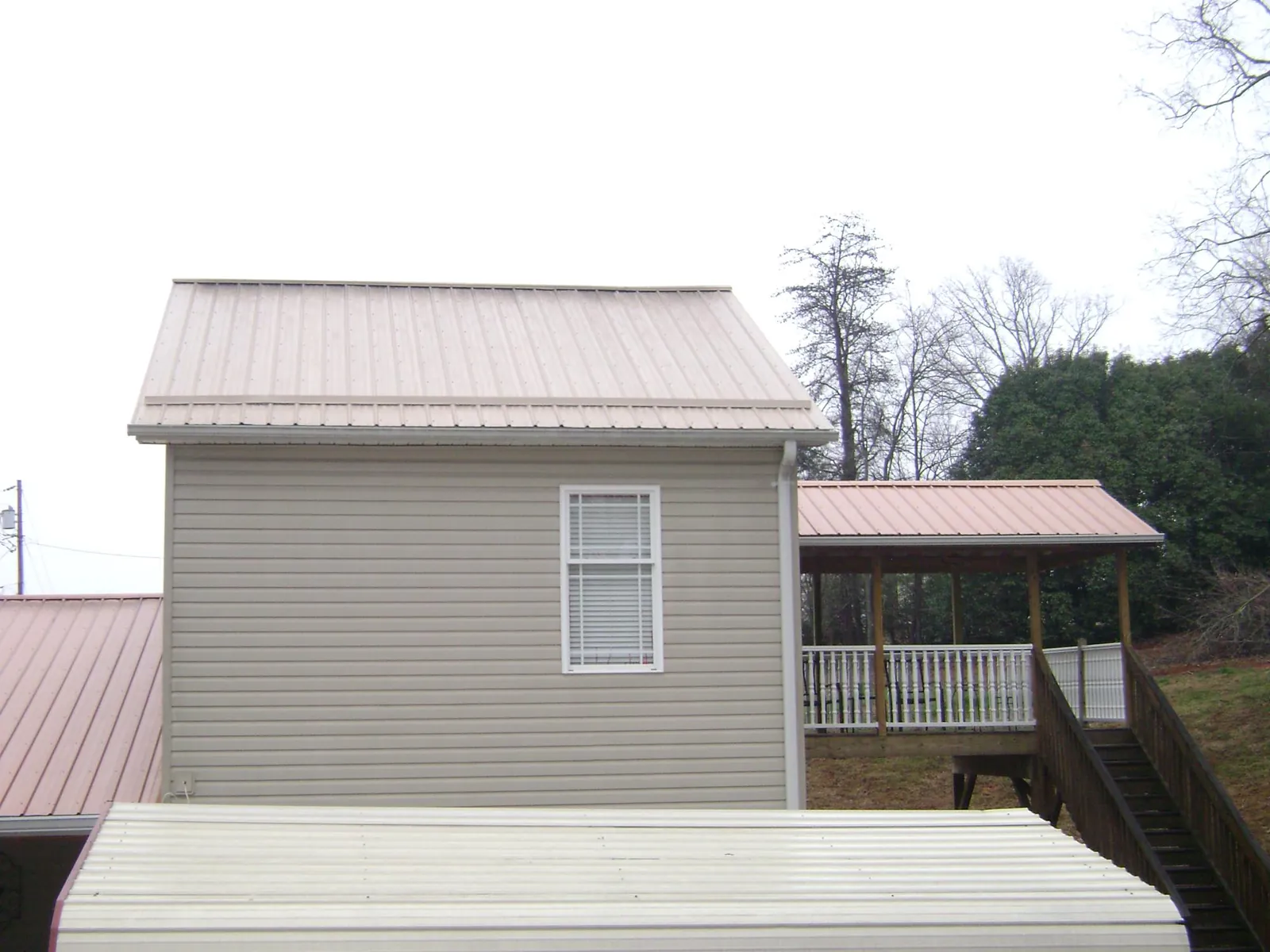 Tan metal roofs on a two story addition and attached porch, from a Roof Replacement job in Claysville