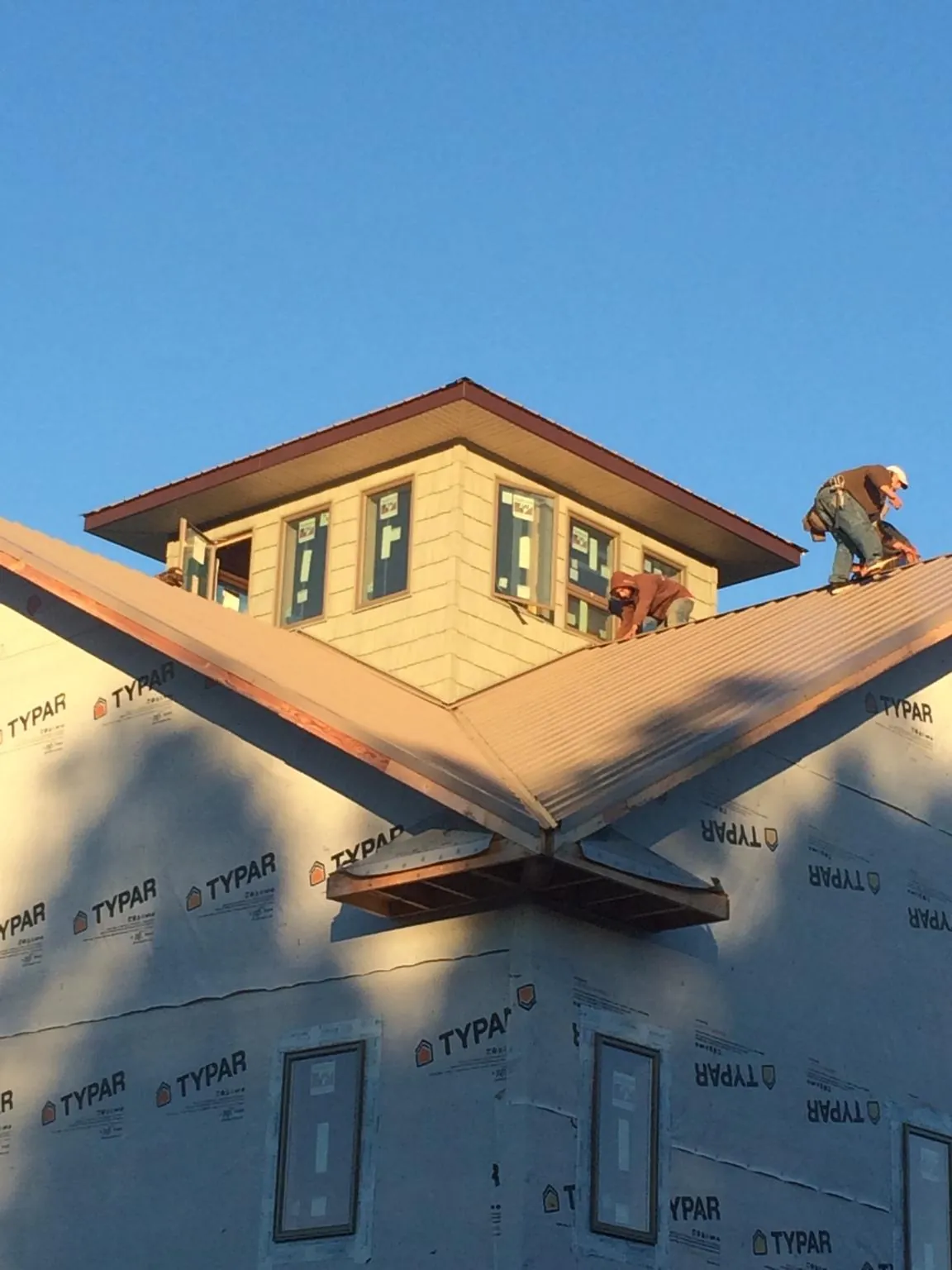 Roofers working around a rooftop cupola on a new metal roof at sunset — Roof Waterproofing in Claysville by Roofing Brothers
